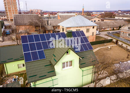 Aerial view of  house cottage with blue shiny solar photo voltaic panels system on the roof. Renewable ecological green energy production concept. Stock Photo