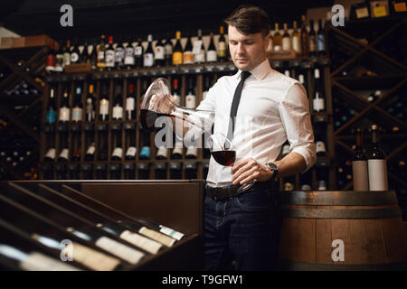 awesome good looking sommelier pouring wine in the glass to taste it. close up photo.hobby concept Stock Photo