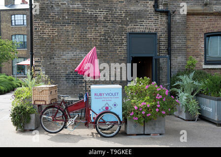 Ruby Violet Ice Cream bicycle tricycle with red sunshade next to planters in front of shop Kings Cross London England Britain UK Stock Photo