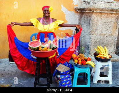 friendly smiling fruit vendor in a colourful dress selling fruit on the street Cartagena, Colombia Stock Photo