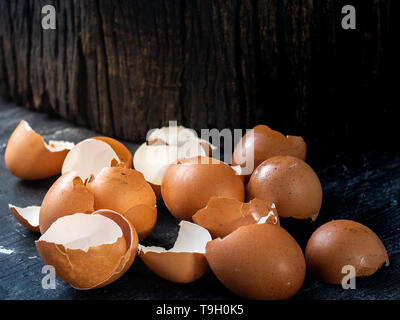 Egg shells on dark wooden plank and log with empty space. Stock Photo