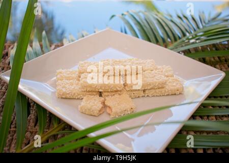 White chocolate biscuit with coconut on a plate, a delicious summer snack. Stock Photo