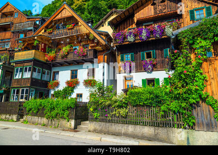 Popular touristic village street view, flowery wooden houses with ornamental gardens and entrances in famous Hallstatt, Salzkammergut region, Austria, Stock Photo