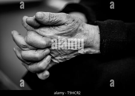 Old woman crossed fingers close up, wrinkled skin - black and white Stock Photo
