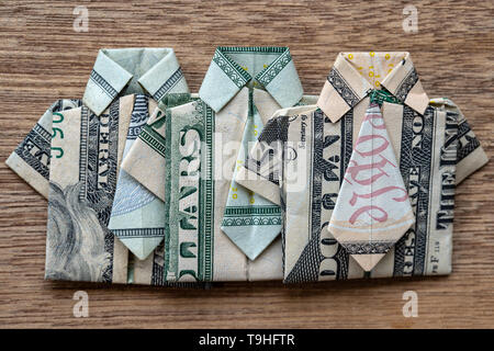 Origami shirt made of dollar banknote on wooden background. Close up. Dollar bill T-shirt Stock Photo