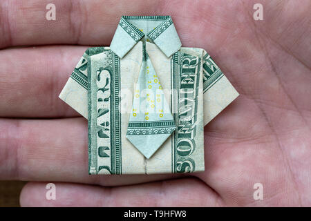 Origami shirt made of dollar banknote on hand background. Close up. Dollar bill T-shirt Stock Photo