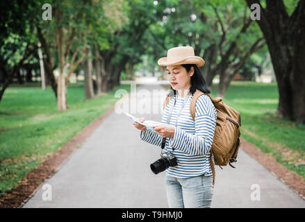 Asian woman backpack traveler use map when traveling at rain forest.Holiday vacation concept.journey lifestyle.solo travel. Stock Photo