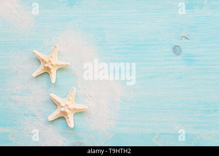 Two starfishes and white sea sand are on the background of blue faded wooden deck. Marine concept Stock Photo