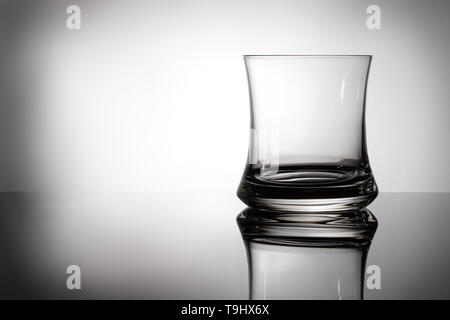 Empty whisky glass in backlight with reflection and free space Stock Photo