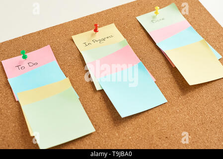 Colored paper stickers with words to do, in progress and done on cork board background. Planning concept Stock Photo