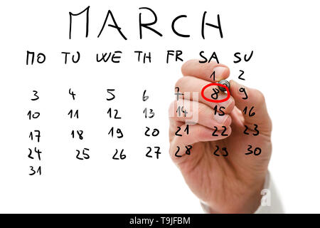 Male hand marking on a monthly calendar, placed on a virtual screen, the date of March 8, International Women's Day or Mother's Day. Stock Photo
