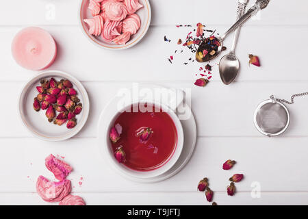Floral tea in a cup, dried roses and other tea accessories on the white background, top ivew Stock Photo