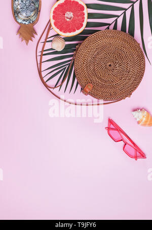 Summer accessories on the pink background. Creative composition with round bag, palm leaf and other Stock Photo