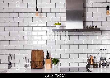 Modern kitchen with brick white tile wall and differet utensils on the counter. Stock Photo