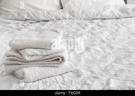 Clean white towels on the white bed close-up. Stock Photo