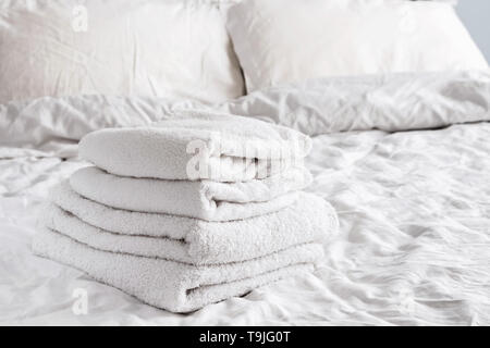 Clean white towels on the white bed close-up. Stock Photo
