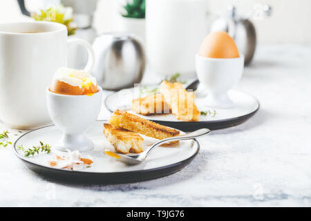 Soft boiled egg for breakfast with toasts and coffee cup in background Stock Photo