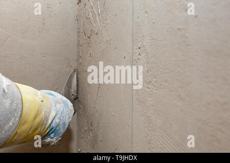 Hand with a spatula in the process of leveling the raw plaster. Stock Photo