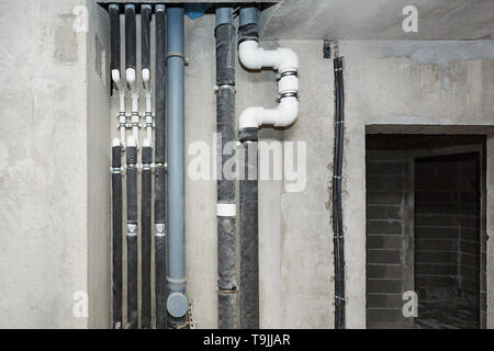 Pipes of heating and water supply system on the background of a concrete wall. Stock Photo