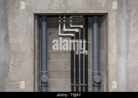 Pipes of heating and water supply system on the background of a concrete wall. Stock Photo