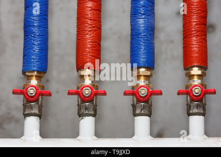 Wiring of hot and cold water supply on the background of a concrete wall. Stock Photo