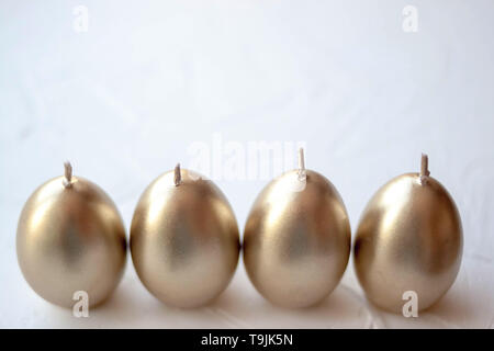 Easter golden egg candles on white background. Text copy space. Selective soft fokus. Stock Photo