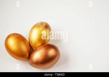 Three gold and bronze Easter eggs on a white background Selective soft focus. Copy space. Stock Photo