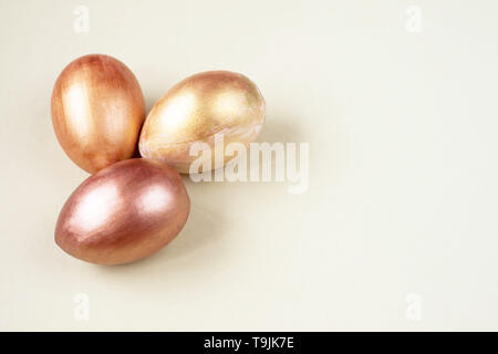 Three gold and bronze Easter eggs on a white background. Selective soft focus. Copy space. Stock Photo