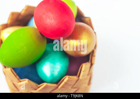 Colorful handmade painted Easter eggs in wicker basket on white background. Festive tradition.Text copy space. Selective soft focus. Stock Photo