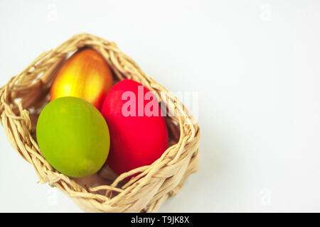 Colorful handmade painted Easter eggs in wicker basket on white background. Festive tradition. Text copy space. Selective soft focus. Stock Photo