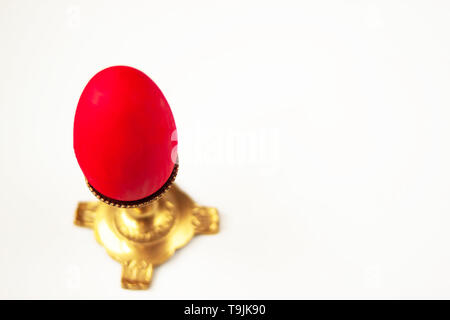 One red easter egg in candleholder eggs on light background. Festive tradition. Text copy space. Selective soft focus. Stock Photo
