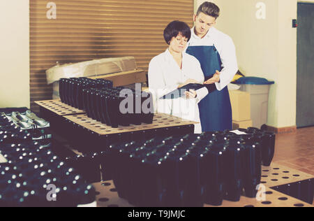 Happy employees checking number of wine bottles at sparkling wine factory Stock Photo