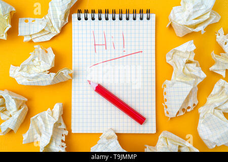 Red pencil and notebook on a yellow background. Crumpled sheets of paper. Stock Photo