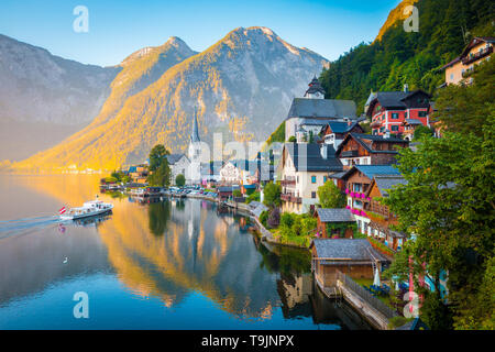 Classic postcard view of famous Hallstatt lakeside town in the Alps with traditional passenger ship in early morning light at sunrise, Austria Stock Photo