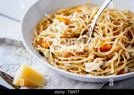 Quick and delicious italian pasta spaghetti with fried eggs, pangrattato and grated parmesan on white plate close-up.Fresh homemade food Stock Photo
