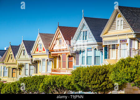 Classic postcard view of famous Painted Ladies, a row of colorful Victorian houses located near scenic Alamo Square, on a beautiful sunny day with blu Stock Photo