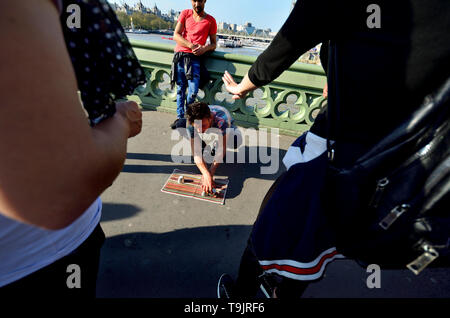 London, England, UK. Illegal Cup and Ball / 3 Cups Trick on Westminster Bridge, trying to con money from passing tourists on a Bank Holiday