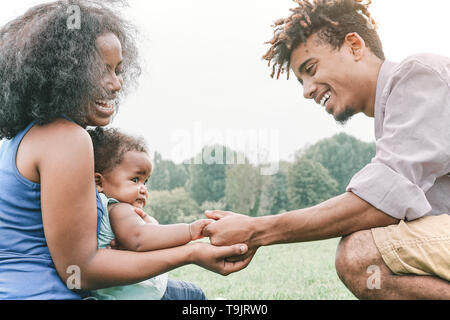 Happy family holding hands together in a park outdoor - Mother and father with their daughter enjoying a weekend day - Love and happiness concept