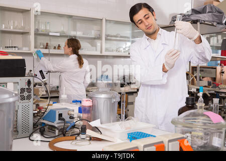 Male chemist working in laboratory, analyzing liquid samples in test flasks Stock Photo
