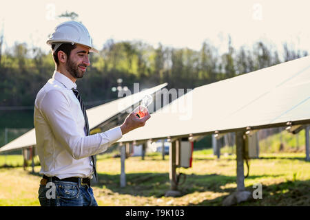 Technical expert in solar photovoltaic panels, remote control performs routine actions to monitor the system using clean renewable energy in the hand  Stock Photo