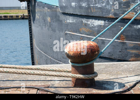Rusty bollard with blue and grey rope around it Stock Photo