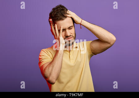 handsome unhappy man having very strong pain and holding pills, tablets. guy has high blood pressure. close up photo. studio shot.useless medicine, symptom Stock Photo