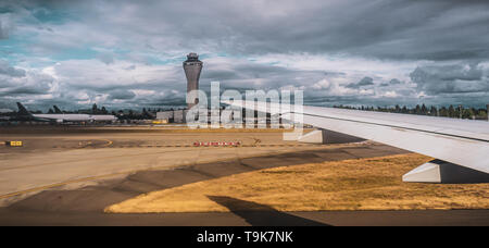 Airport scenery. Airplane ready to take off with air traffic control tower in the distance. Cloudy and stormy day. Stock Photo