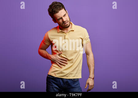 angry guy having painful stomachache, chronic gastritis. young handsome man has infection,man suffering from vomiting. close up photo Stock Photo