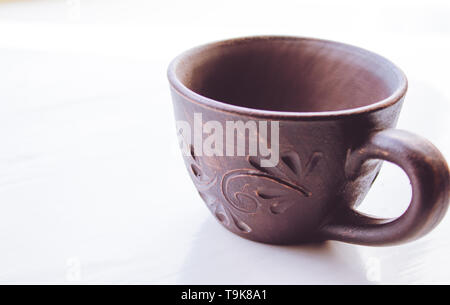 Clay cup stands on a white background. Close-up. Stock Photo