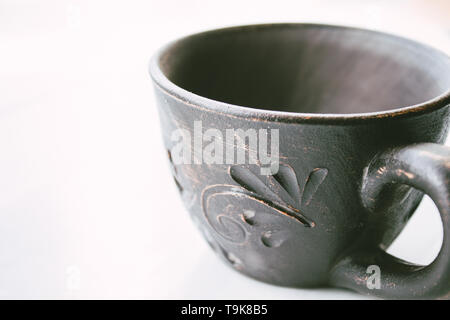 Clay cup stands on a white background. Close-up. Stock Photo