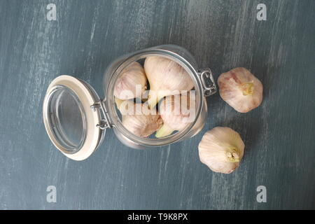 Heads of garlic in a kilner jar on a blue distressed wood kitchen table. Stock Photo