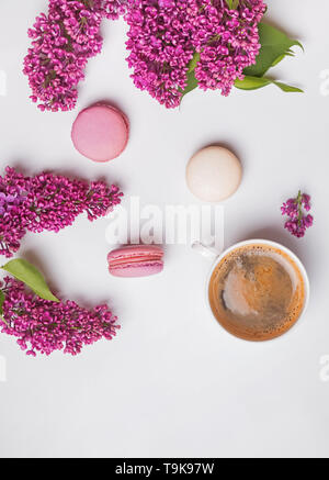 Creative spring composition with coffee, macarons and lilac flowers on the white background Stock Photo
