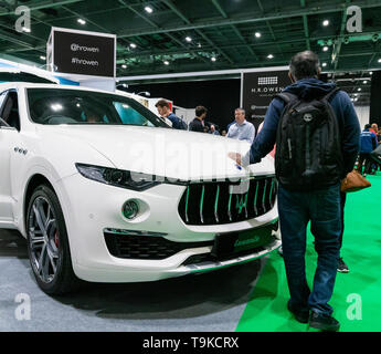 18th May 2019. London, UK. A man holds his hand on luxury Maserati Levante SUV at London Motor Show 2019.