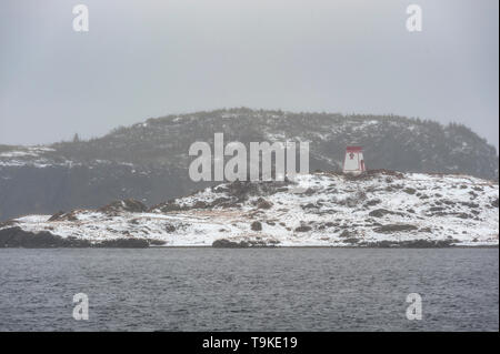 Lighthouse on snow covered shoreline Stock Photo